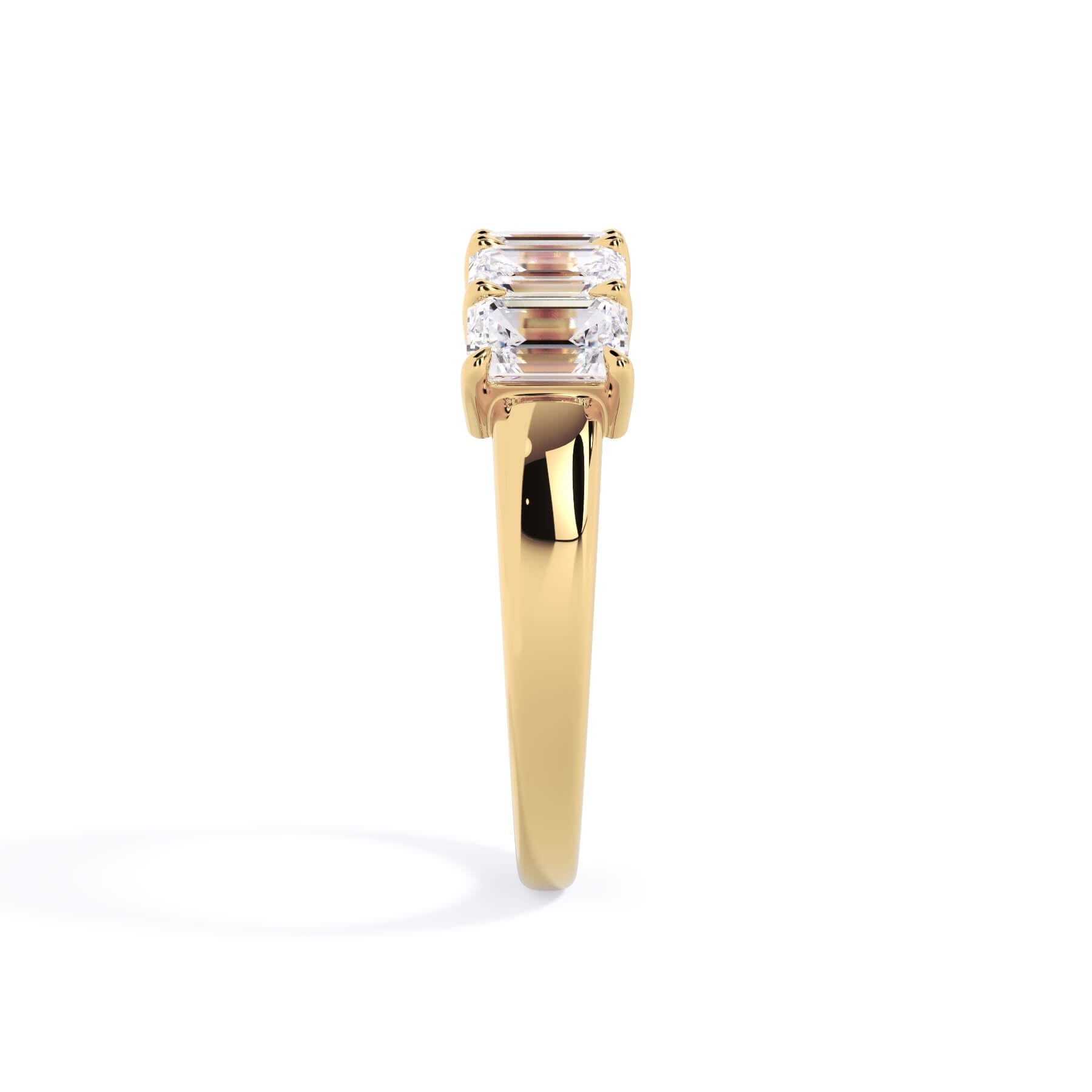 A picture of a five stone diamond wedding ring with emerald cut diamonds that are shared prong set in yellow gold on a white background with a side profile view.