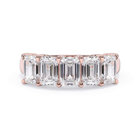 A picture of a five stone diamond wedding ring with emerald cut diamonds that are shared prong set in rose gold on a white background with the ring facing forward, lying down.