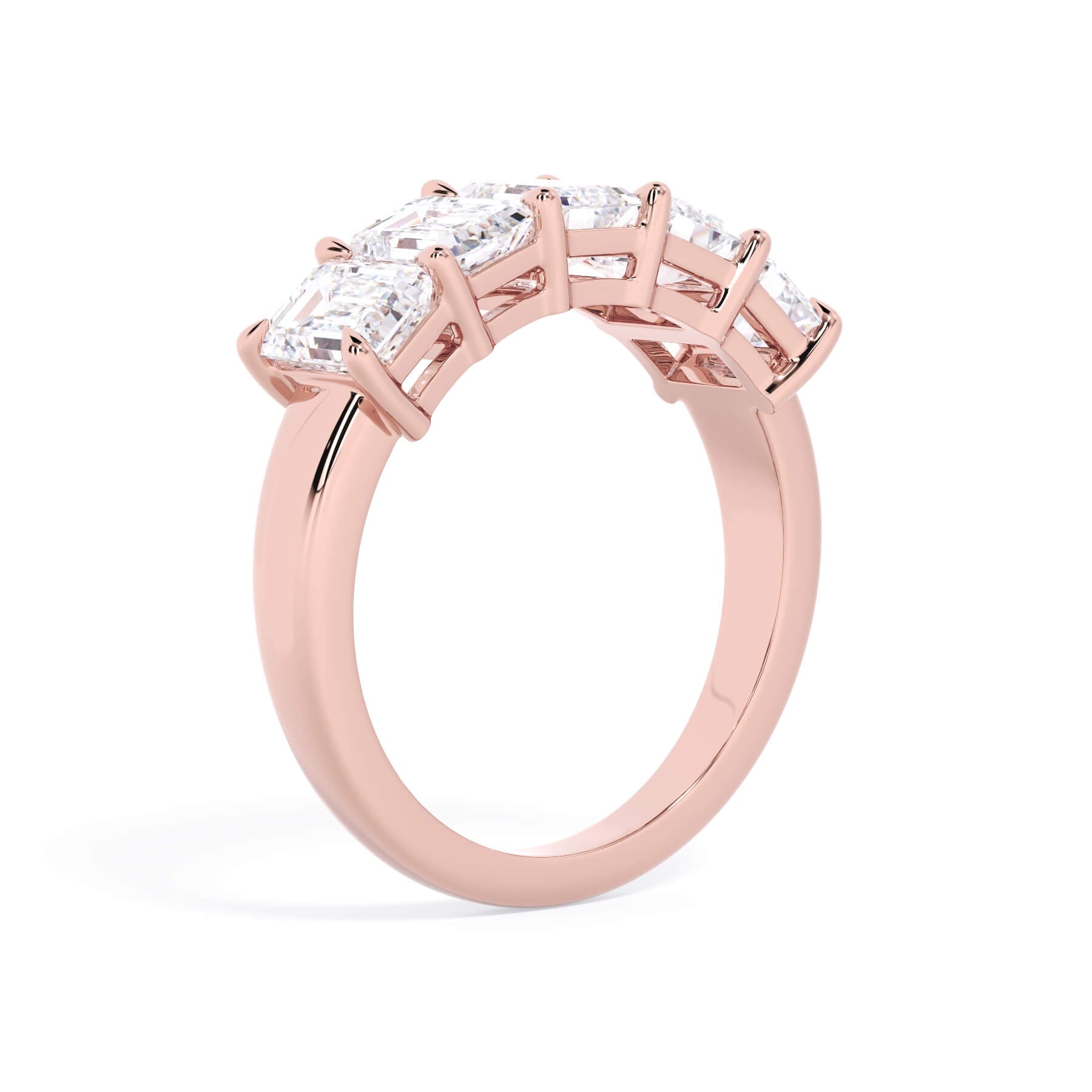 A picture of a five stone diamond wedding ring with emerald cut diamonds that are shared prong set in rose gold on a white background with a slightly angled, through the finger view.