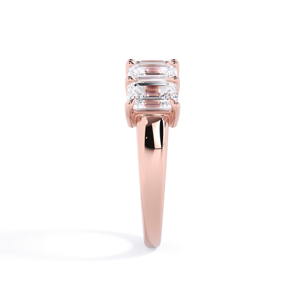 A picture of a five stone diamond wedding ring with emerald cut diamonds that are shared prong set in rose gold on a white background with a side profile view.
