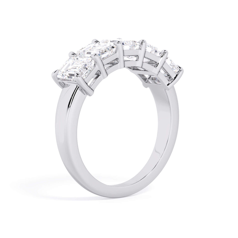 A picture of a five stone diamond wedding ring with emerald cut diamonds that are shared prong set in white gold or platinum on a white background with a slightly angled, through the finger view.