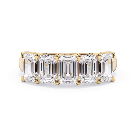 A picture of a five stone diamond wedding ring with emerald cut diamonds that are shared prong set in yellow gold on a white background with the ring facing forward, lying down.