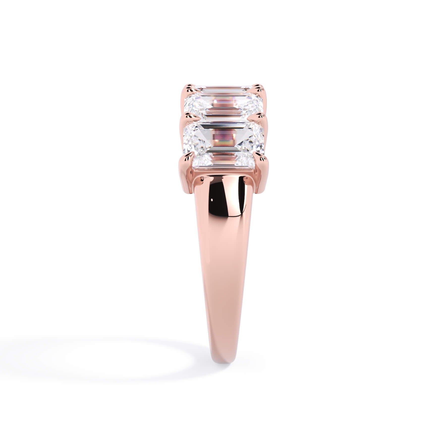 A picture of a five stone diamond wedding ring with emerald cut diamonds that are shared prong set in rose gold on a white background with a side profile view.