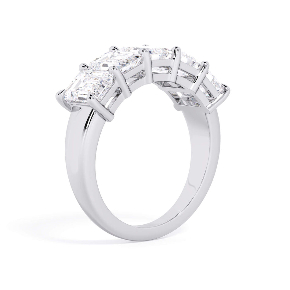 A picture of a five stone diamond wedding ring with emerald cut diamonds that are shared prong set in white gold or platinum on a white background with a slightly angled, through the finger view.