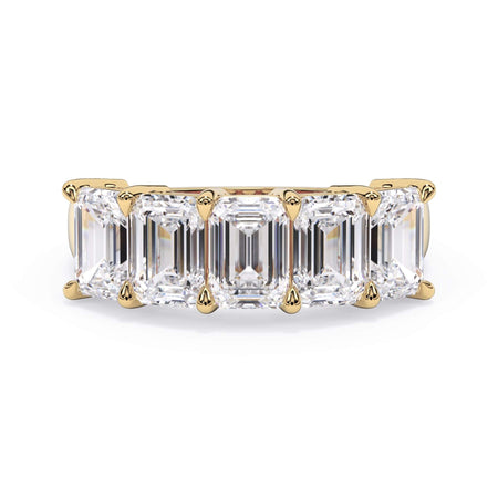 A picture of a five stone diamond wedding ring with emerald cut diamonds that are shared prong set in yellow gold on a white background with the ring facing forward, lying down.