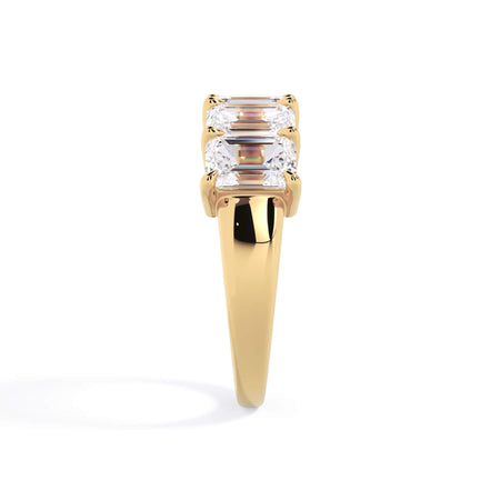 A picture of a five stone diamond wedding ring with emerald cut diamonds that are shared prong set in yellow gold on a white background with a side profile view.