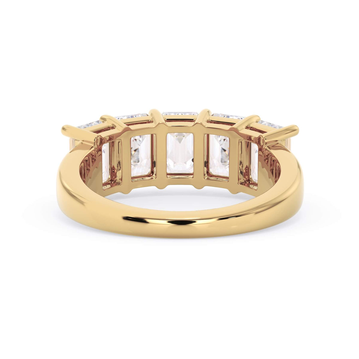 A picture of a five stone diamond wedding ring with emerald cut diamonds that are shared prong set in yellow gold on a white background with a view of the underside of the ring.