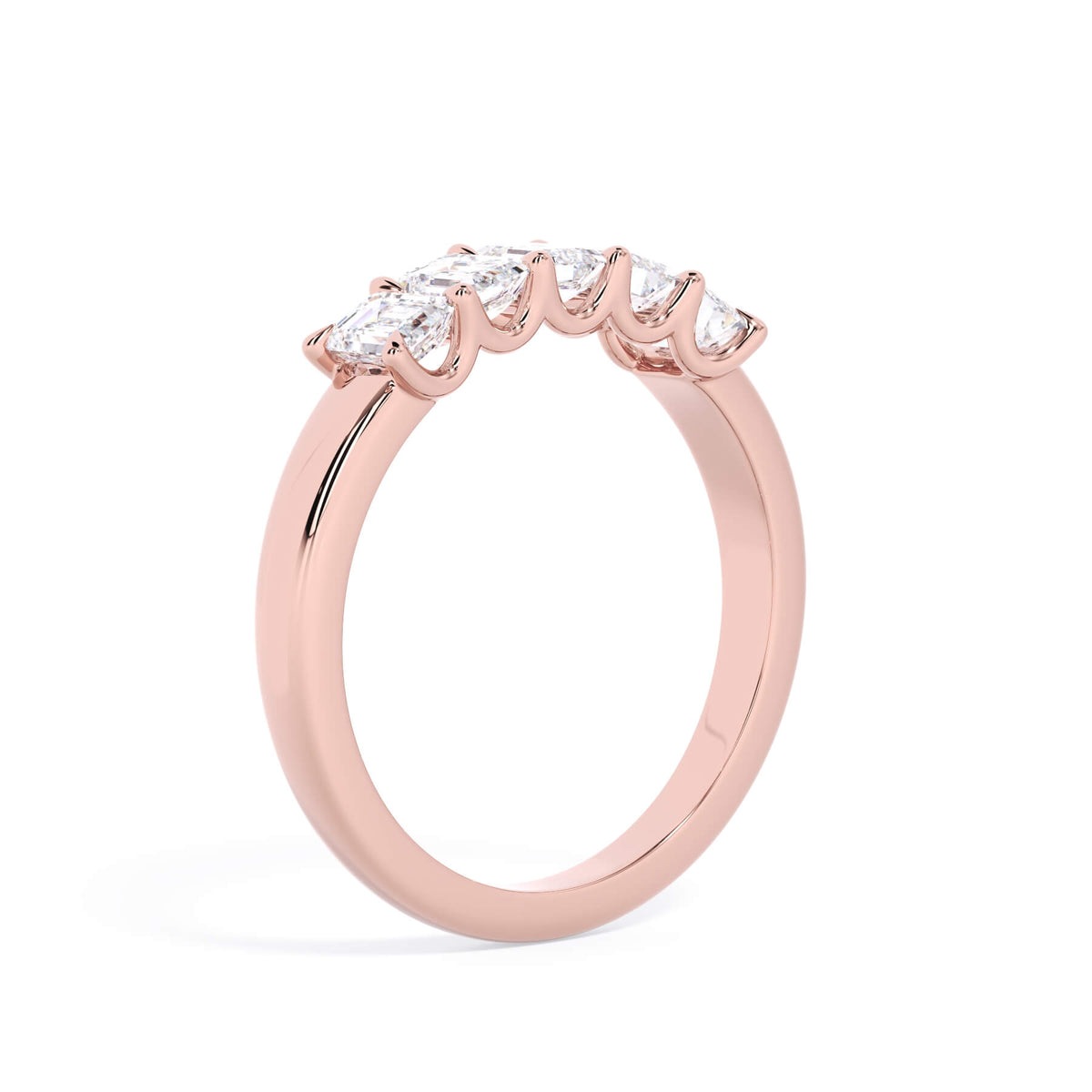 A picture of a five stone diamond wedding ring with emerald cut diamonds that are u prong set in rose gold on a white background with a slightly angled, through the finger view.