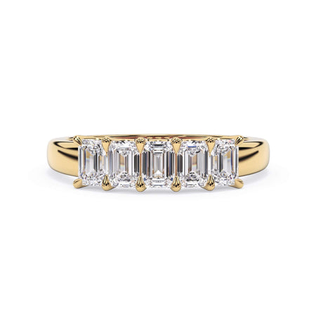 A picture of a five stone diamond wedding ring with emerald cut diamonds that are u prong set in yellow gold on a white background with the ring facing forward, lying down.