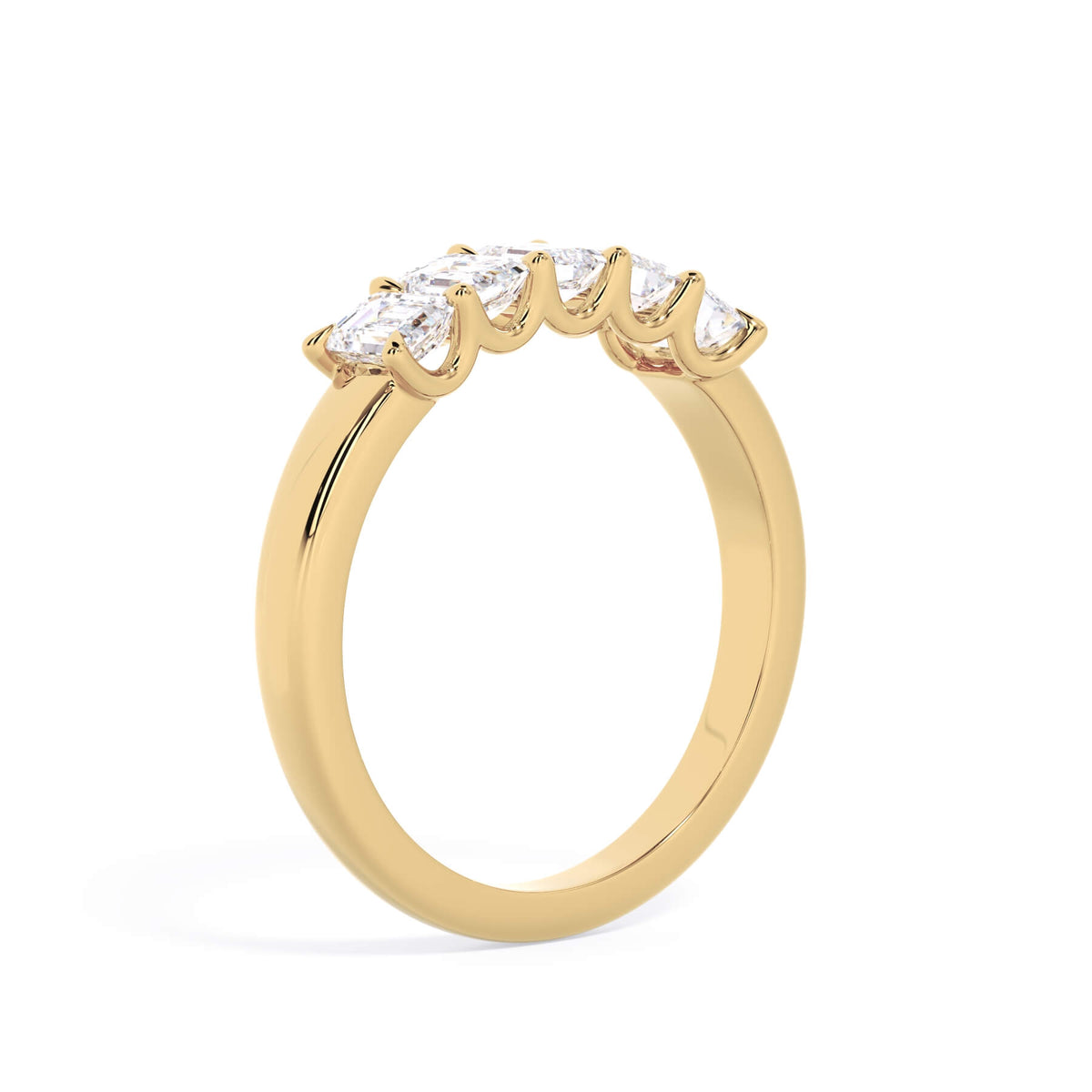 A picture of a five stone diamond wedding ring with emerald cut diamonds that are u prong set in yellow gold on a white background with a slightly angled, through the finger view.
