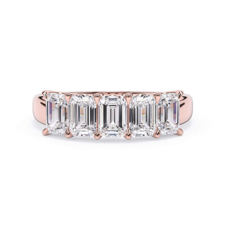 A picture of a five stone diamond wedding ring with emerald cut diamonds that are u prong set in rose gold on a white background with the ring facing forward, lying down.
