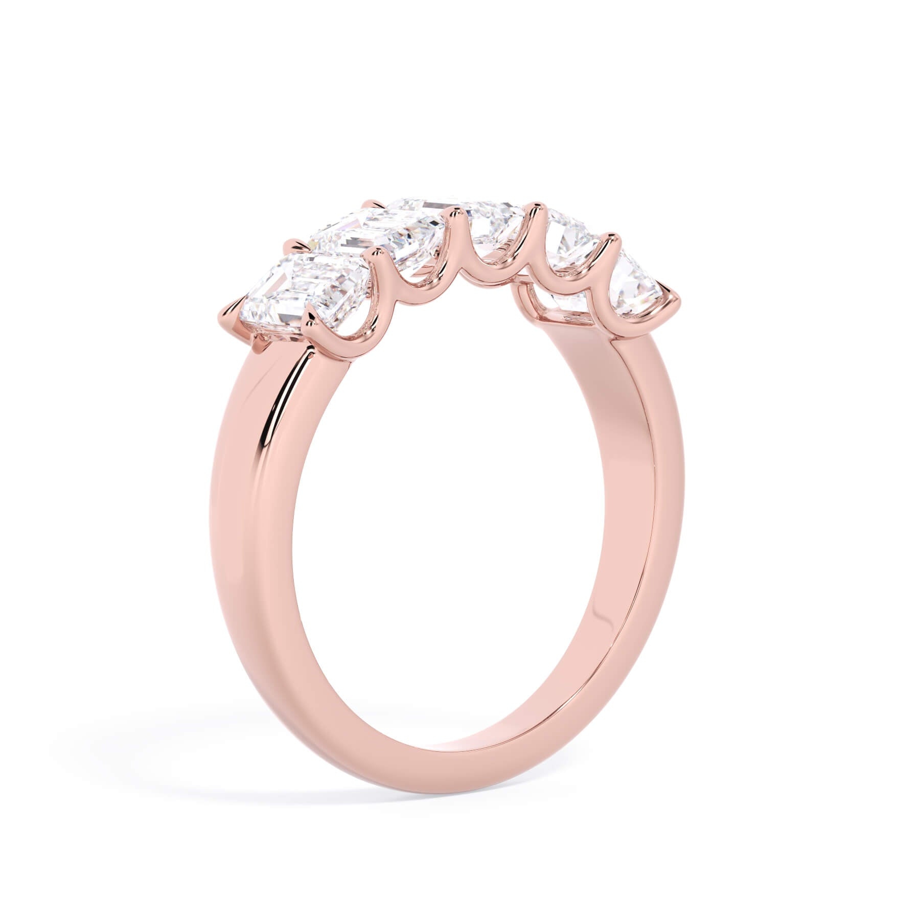 A picture of a five stone diamond wedding ring with emerald cut diamonds that are u prong set in rose gold on a white background with a slightly angled, through the finger view.