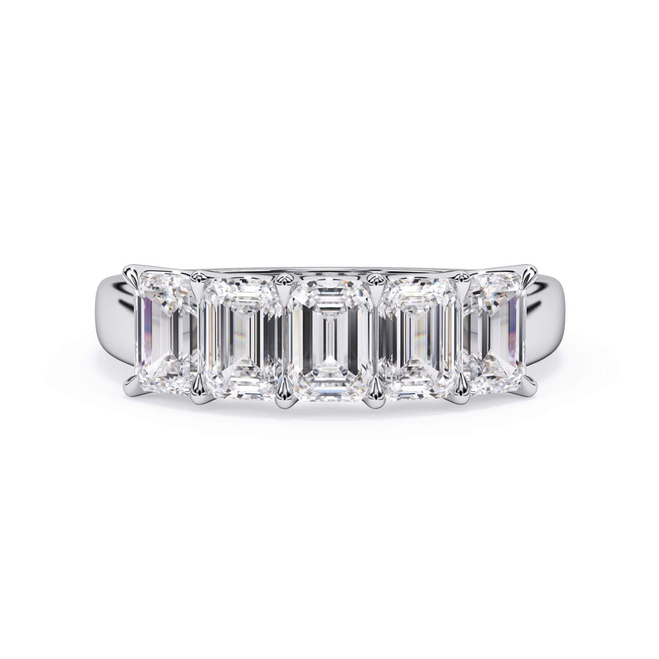 A picture of a five stone diamond wedding ring with emerald cut diamonds that are u prong set in white gold or platinum on a white background with the ring facing forward, lying down.