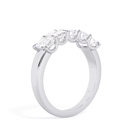 A picture of a five stone diamond wedding ring with emerald cut diamonds that are u prong set in white gold or platinum on a white background with a slightly angled, through the finger view.