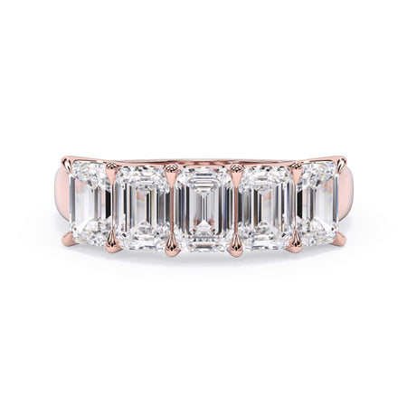 A picture of a five stone diamond wedding ring with emerald cut diamonds that are u prong set in rose gold on a white background with the ring facing forward, lying down.