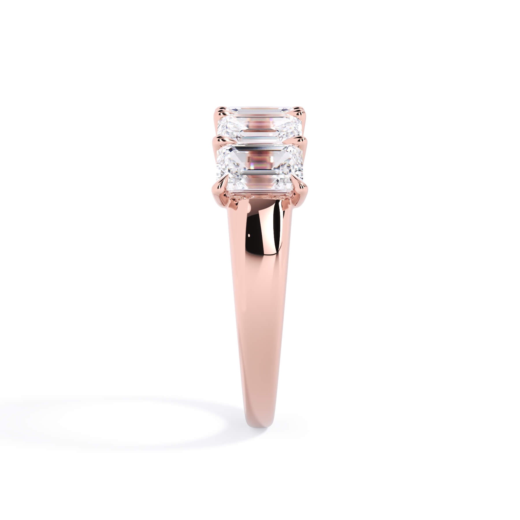 A picture of a five stone diamond wedding ring with emerald cut diamonds that are u prong set in rose gold on a white background with a side profile view.