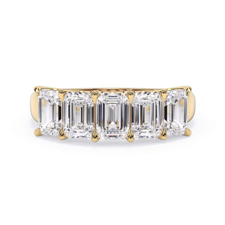A picture of a five stone diamond wedding ring with emerald cut diamonds that are u prong set in yellow gold on a white background with the ring facing forward, lying down.