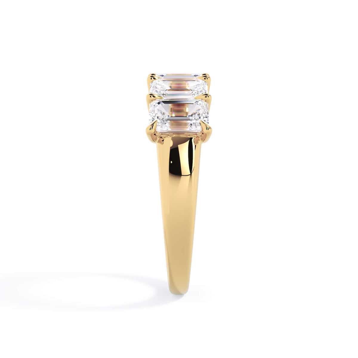 A picture of a five stone diamond wedding ring with emerald cut diamonds that are u prong set in yellow gold on a white background with a side profile view.