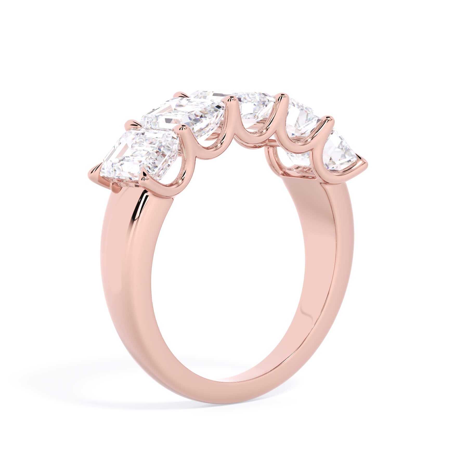 A picture of a five stone diamond wedding ring with emerald cut diamonds that are u prong set in rose gold on a white background with a slightly angled, through the finger view.