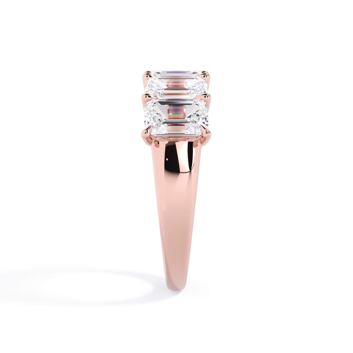 A picture of a five stone diamond wedding ring with emerald cut diamonds that are u prong set in rose gold on a white background with a side profile view.