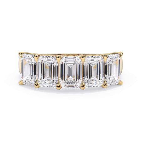 A picture of a five stone diamond wedding ring with emerald cut diamonds that are u prong set in yellow gold on a white background with the ring facing forward, lying down.