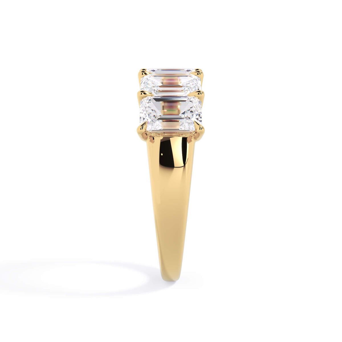 A picture of a five stone diamond wedding ring with emerald cut diamonds that are u prong set in yellow gold on a white background with a side profile view.