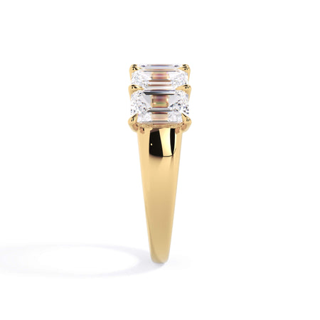 A picture of a five stone diamond wedding ring with emerald cut diamonds that are u prong set in yellow gold on a white background with a side profile view.