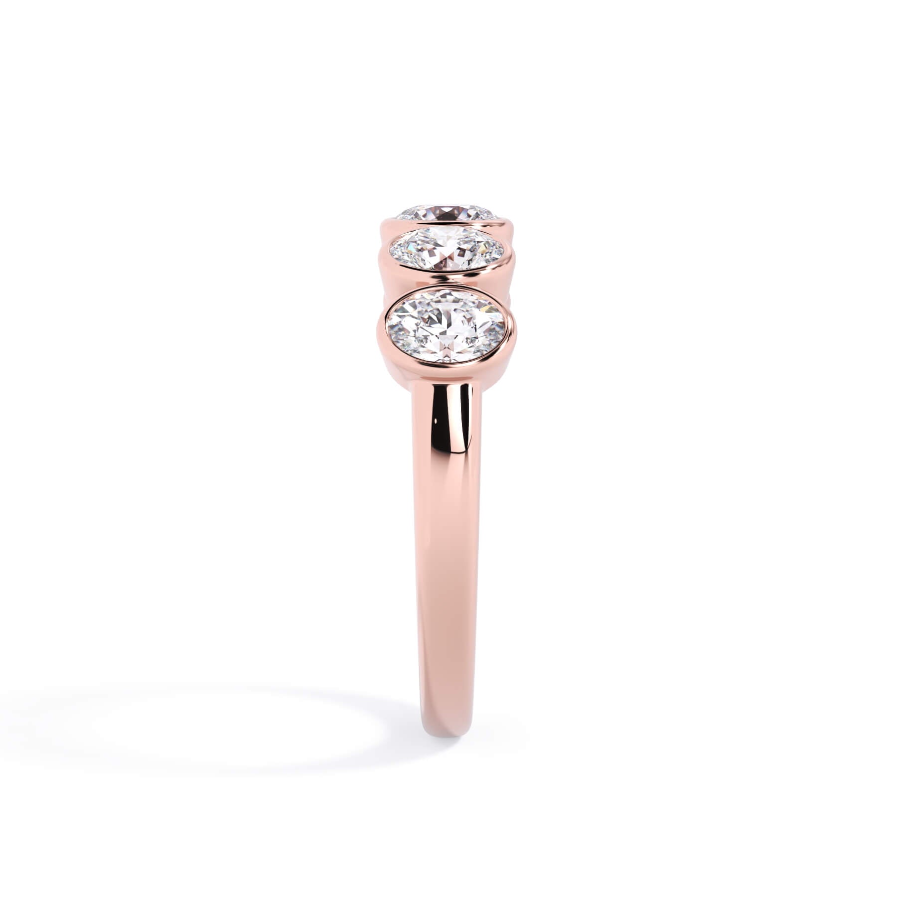 A picture of a five stone diamond wedding ring with oval shape diamonds that are bezel set in rose gold on a white background with a side profile view.