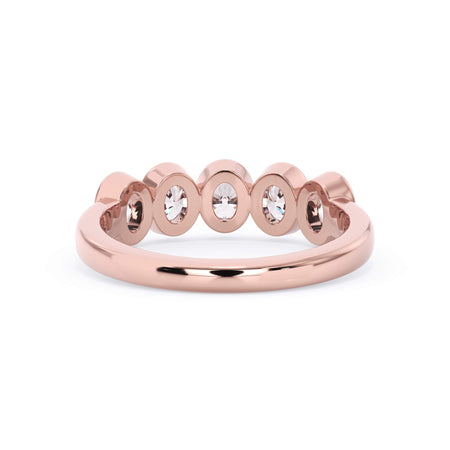 A picture of a five stone diamond wedding ring with oval shape diamonds that are bezel set in rose gold on a white background with a view of the underside of the ring.