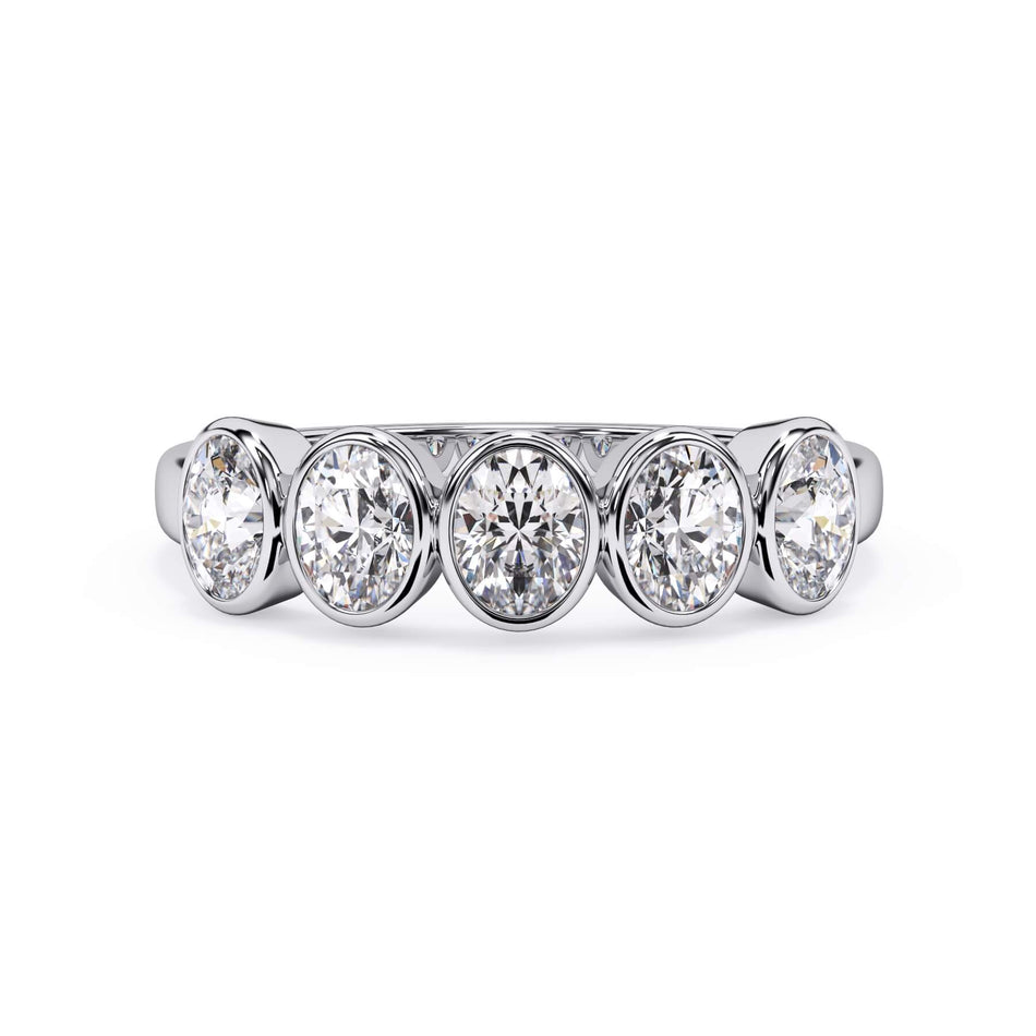 A picture of a five stone diamond wedding ring with oval shape diamonds that are bezel set in white gold or platinum on a white background with the ring facing forward, lying down.