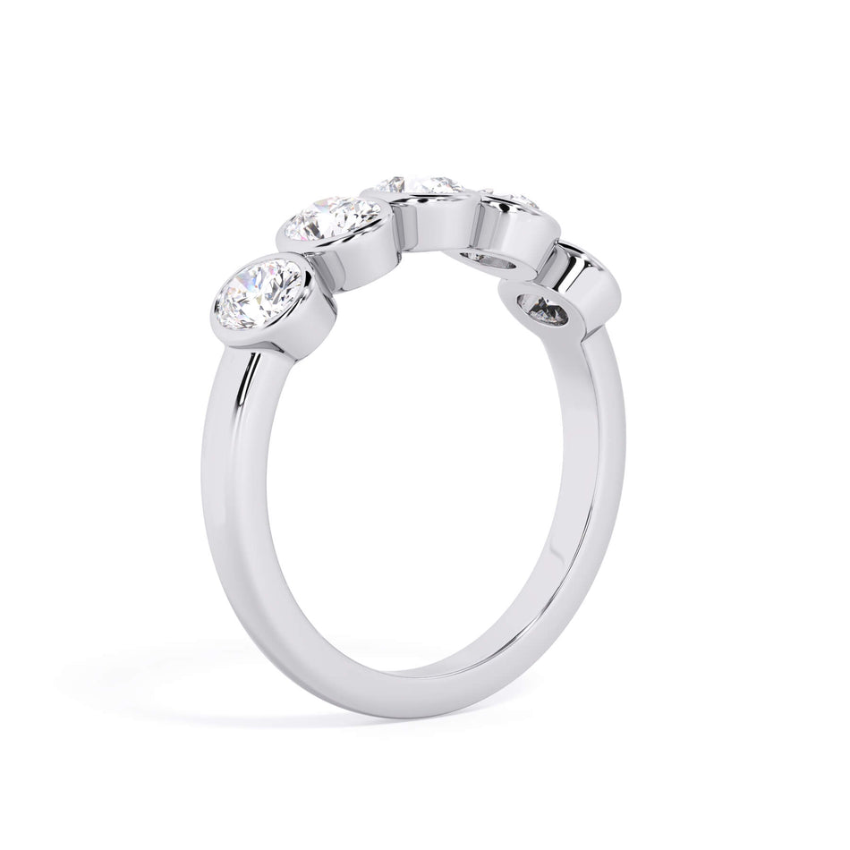 A picture of a five stone diamond wedding ring with oval shape diamonds that are bezel set in white gold or platinum on a white background with a slightly angled, through the finger view.