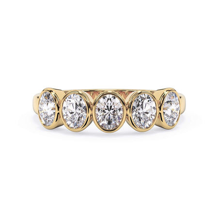 A picture of a five stone diamond wedding ring with oval shape diamonds that are bezel set in yellow gold on a white background with the ring facing forward, lying down.