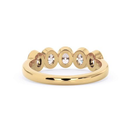 A picture of a five stone diamond wedding ring with oval shape diamonds that are bezel set in yellow gold on a white background with a view of the underside of the ring.
