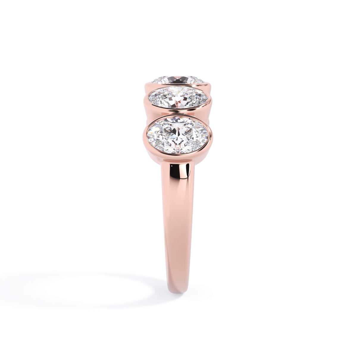 A picture of a five stone diamond wedding ring with oval shape diamonds that are bezel set in rose gold on a white background with a side profile view.