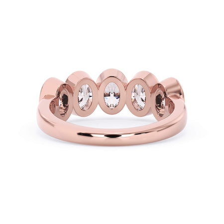 A picture of a five stone diamond wedding ring with oval shape diamonds that are bezel set in rose gold on a white background with a view of the underside of the ring.