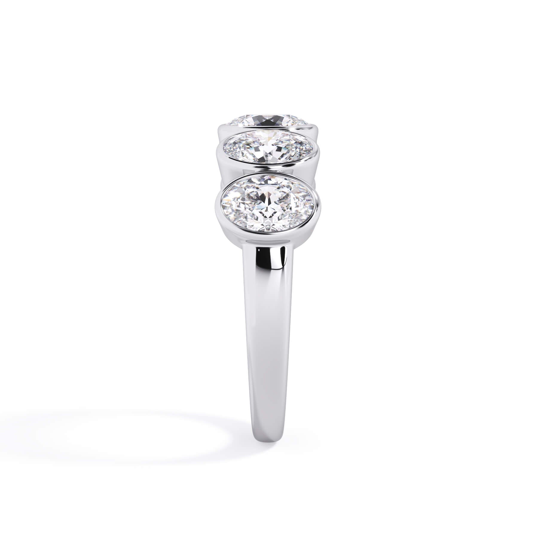 A picture of a five stone diamond wedding ring with oval shape diamonds that are bezel set in white gold or platinum on a white background with a side profile view.