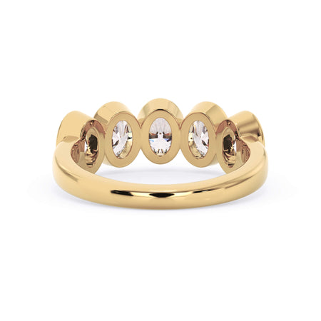 A picture of a five stone diamond wedding ring with oval shape diamonds that are bezel set in yellow gold on a white background with a view of the underside of the ring.