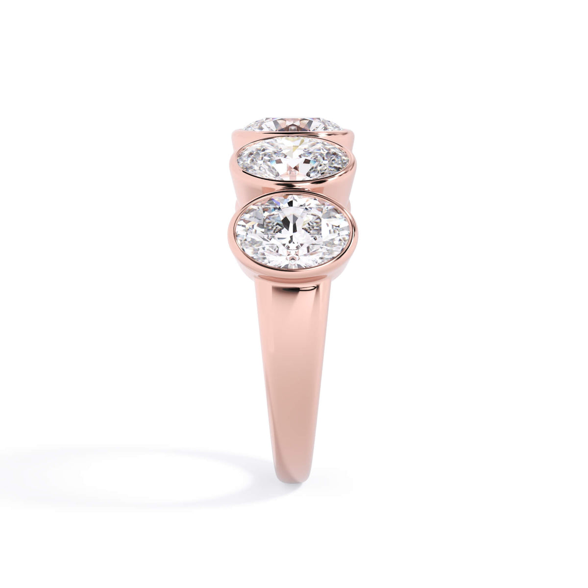 A picture of a five stone diamond wedding ring with oval shape diamonds that are bezel set in rose gold on a white background with a side profile view.