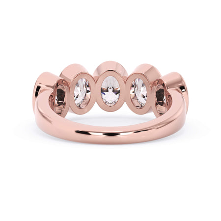 A picture of a five stone diamond wedding ring with oval shape diamonds that are bezel set in rose gold on a white background with a view of the underside of the ring.