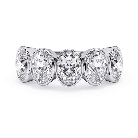 A picture of a five stone diamond wedding ring with oval shape diamonds that are bezel set in white gold or platinum on a white background with the ring facing forward, lying down.