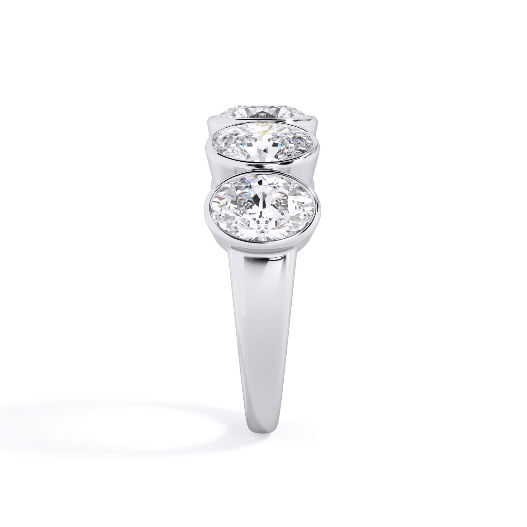 A picture of a five stone diamond wedding ring with oval shape diamonds that are bezel set in white gold or platinum on a white background with a side profile view.