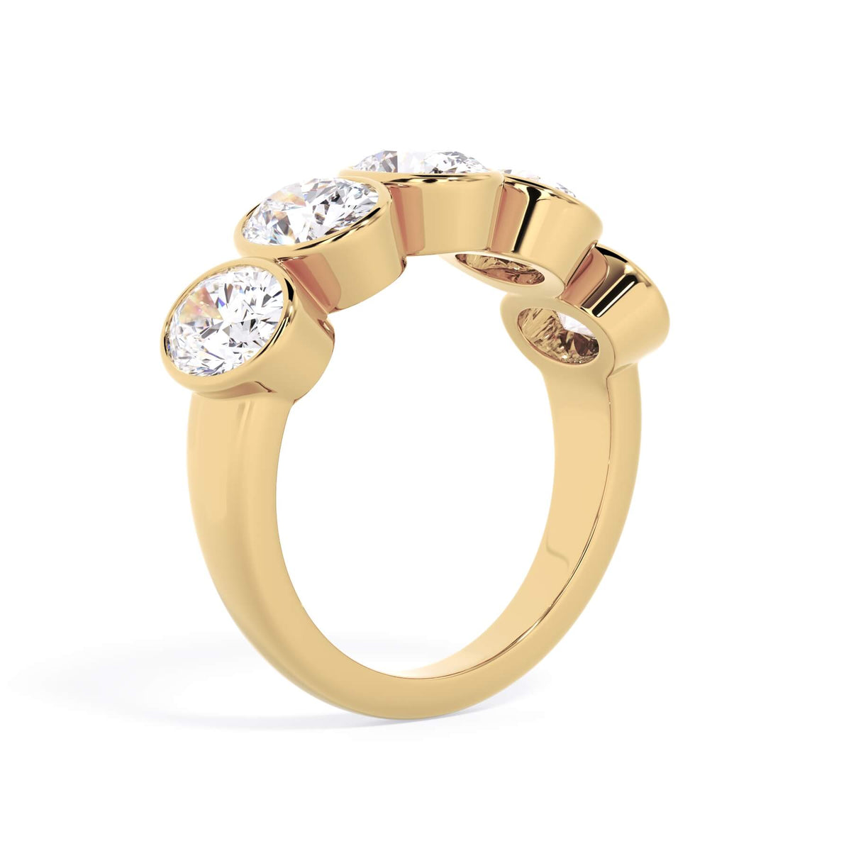 A picture of a five stone diamond wedding ring with oval shape diamonds that are bezel set in yellow gold on a white background with a slightly angled, through the finger view.