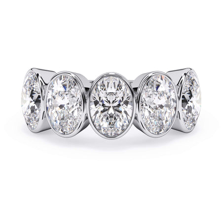A picture of a five stone diamond wedding ring with oval shape diamonds that are bezel set in white gold or platinum on a white background with the ring facing forward, lying down.