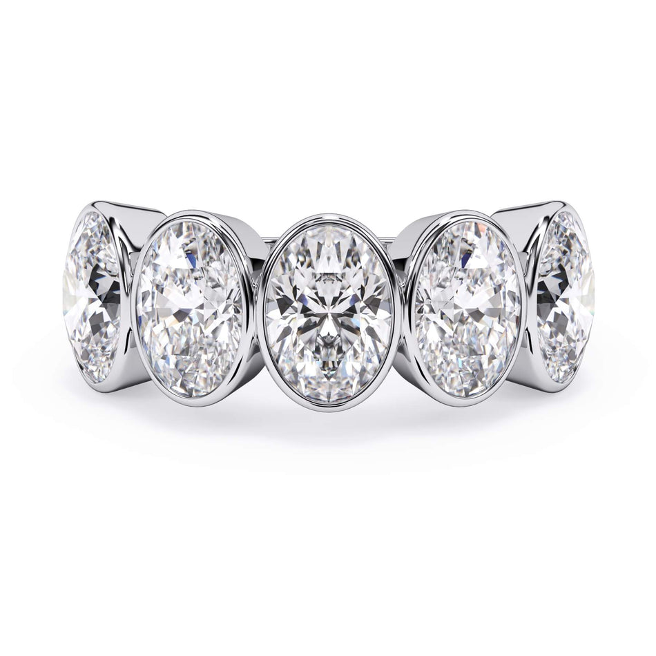 A picture of a five stone diamond wedding ring with oval shape diamonds that are bezel set in white gold or platinum on a white background with the ring facing forward, lying down.