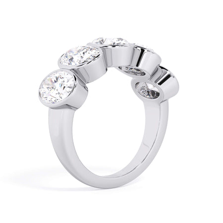 A picture of a five stone diamond wedding ring with oval shape diamonds that are bezel set in white gold or platinum on a white background with a slightly angled, through the finger view.