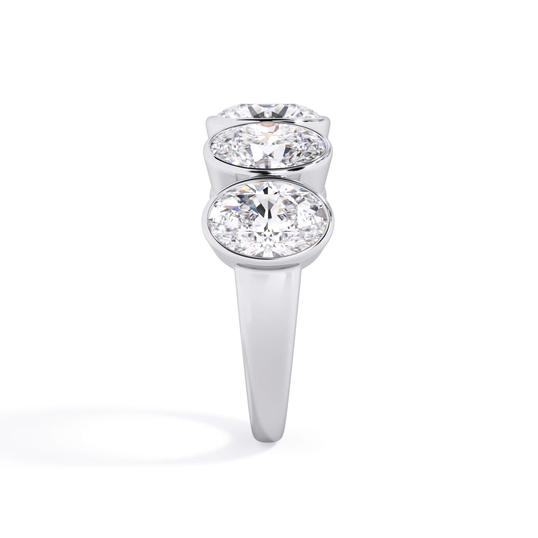 A picture of a five stone diamond wedding ring with oval shape diamonds that are bezel set in white gold or platinum on a white background with a side profile view.