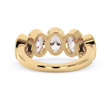 A picture of a five stone diamond wedding ring with oval shape diamonds that are bezel set in yellow gold on a white background with a view of the underside of the ring.