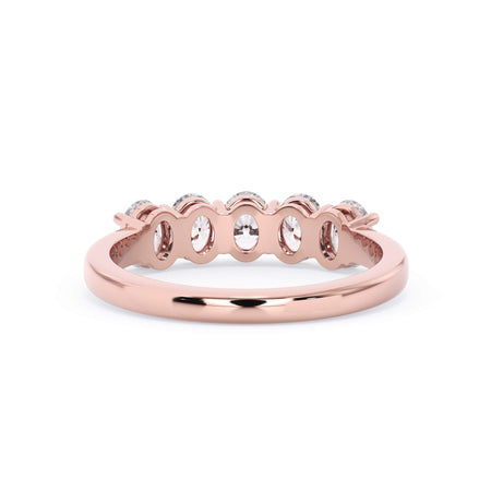 A picture of a five stone diamond wedding ring with oval shape diamonds that are shared prong set in rose gold on a white background with a view of the underside of the ring.