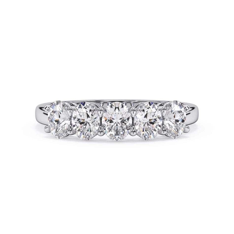 A picture of a five stone diamond wedding ring with oval shape diamonds that are shared prong set in white gold or platinum on a white background with the ring facing forward, lying down.