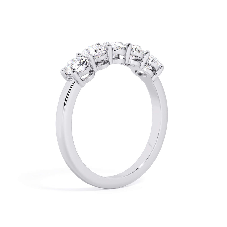 A picture of a five stone diamond wedding ring with oval shape diamonds that are shared prong set in white gold or platinum on a white background with a slightly angled, through the finger view.